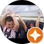 Two children sitting in a moving convertible car with their hands up, appearing to enjoy the ride. A white star in an orange circle is overlaid on the bottom right corner.